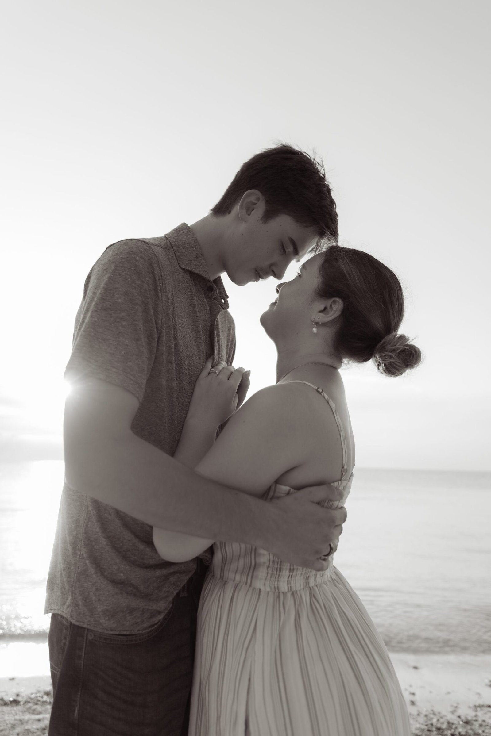Couple embracing by the sea after the proposal, in black and white