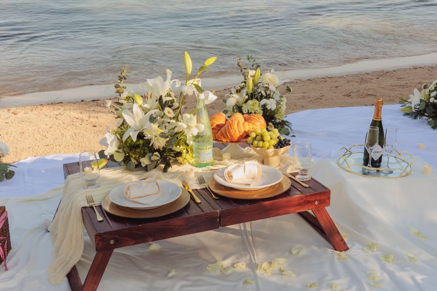 Custom letter board among white florals and petals on the picnic blanket