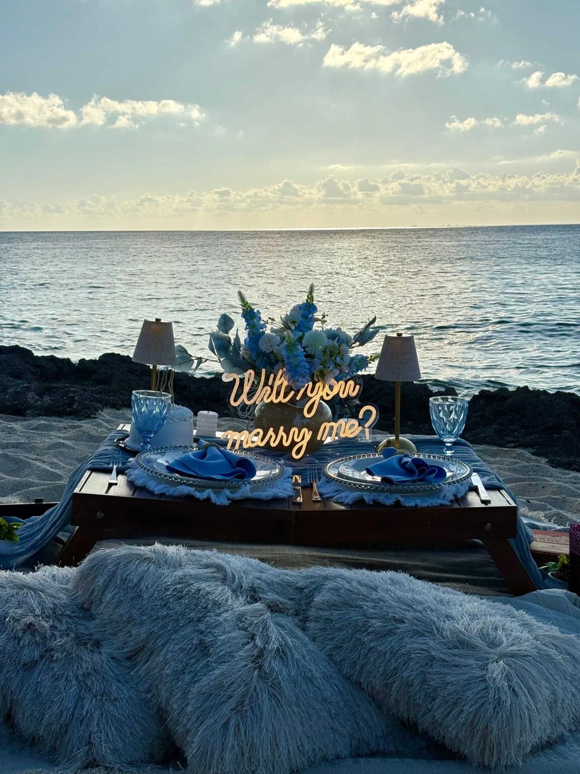 Beach proposal setup with an illuminated “Will you marry me?” sign facing the sea in Cozumel