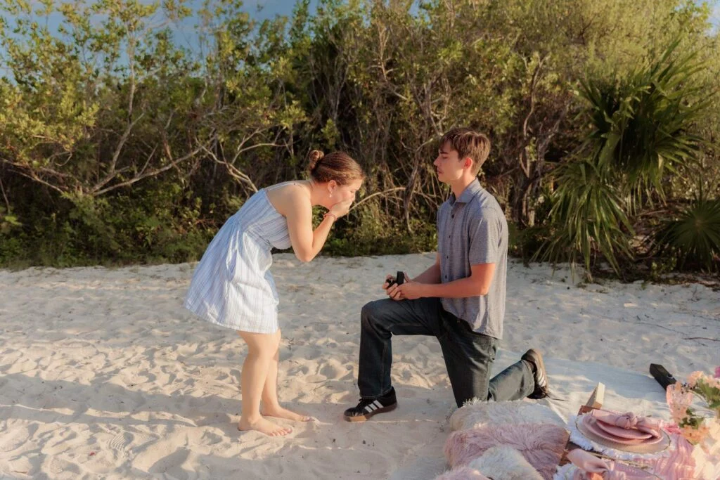 Red rose proposal setup with a fabric path on the beach