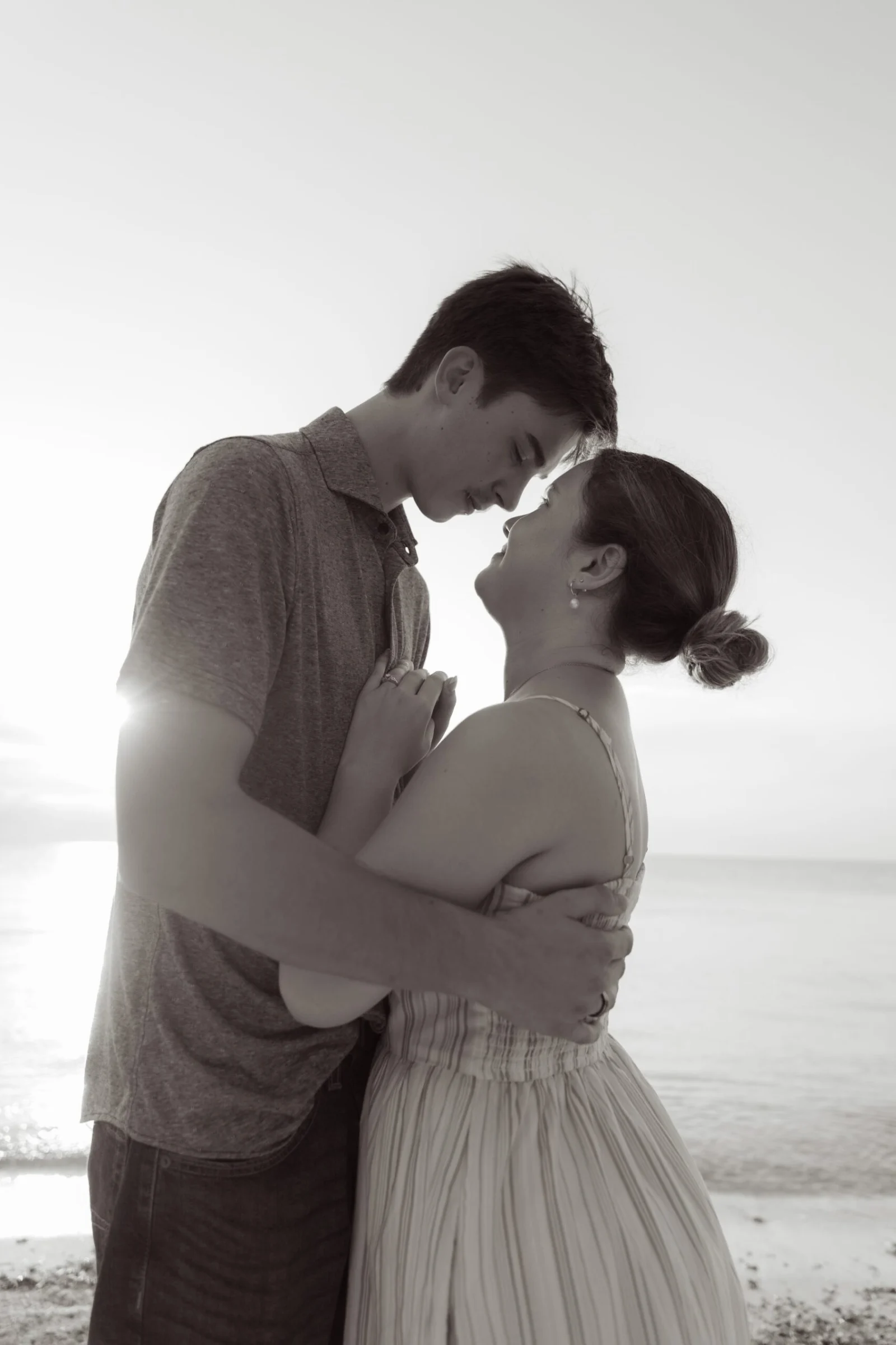 Couple embracing by the sea after the proposal, in black and white